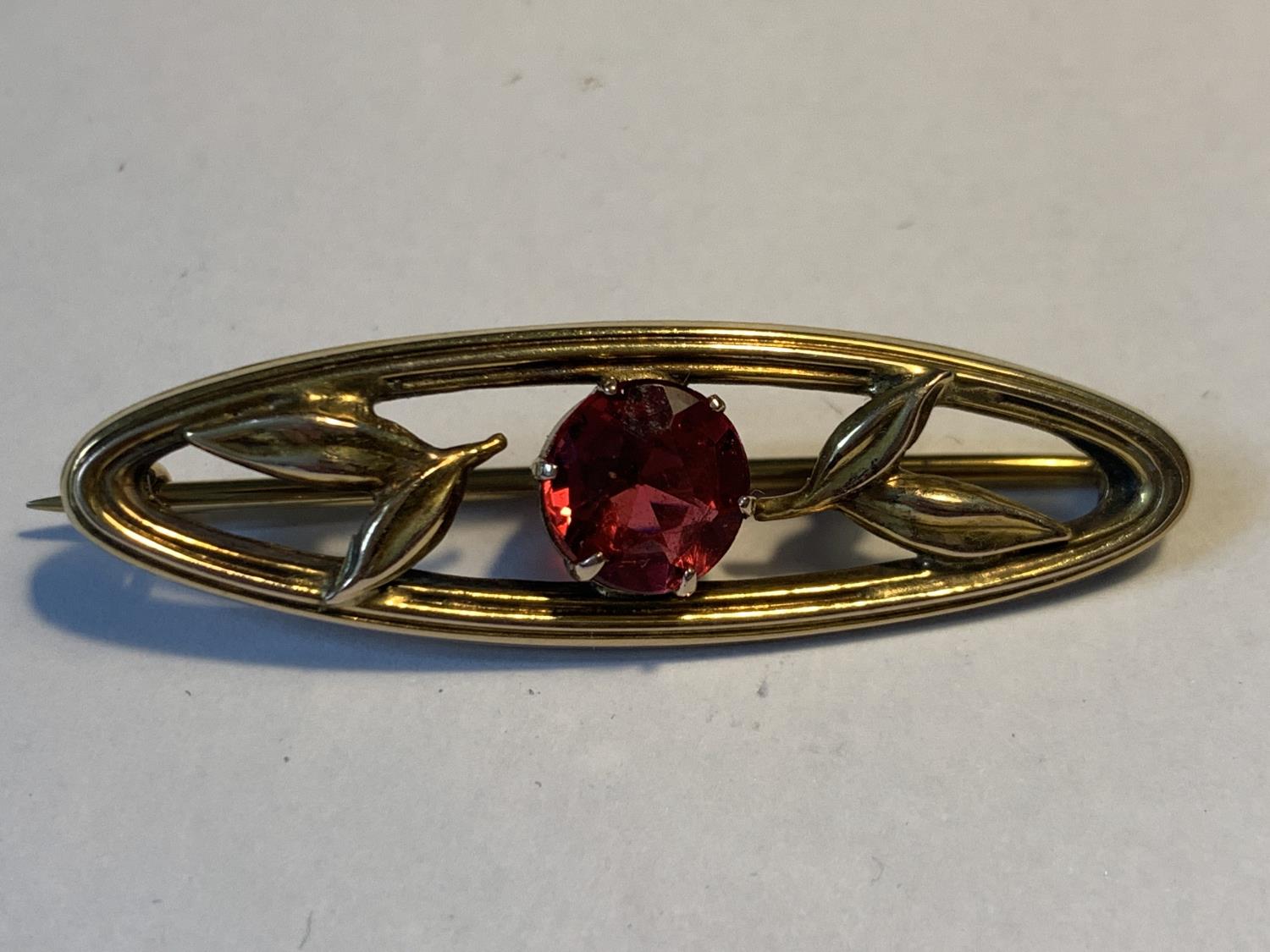A 9 CARAT GOLD BROOCH WITH CENTRE RED STONE GROSS WEIGHT 2.64 GRAMS IN A PRESENTATION BOX