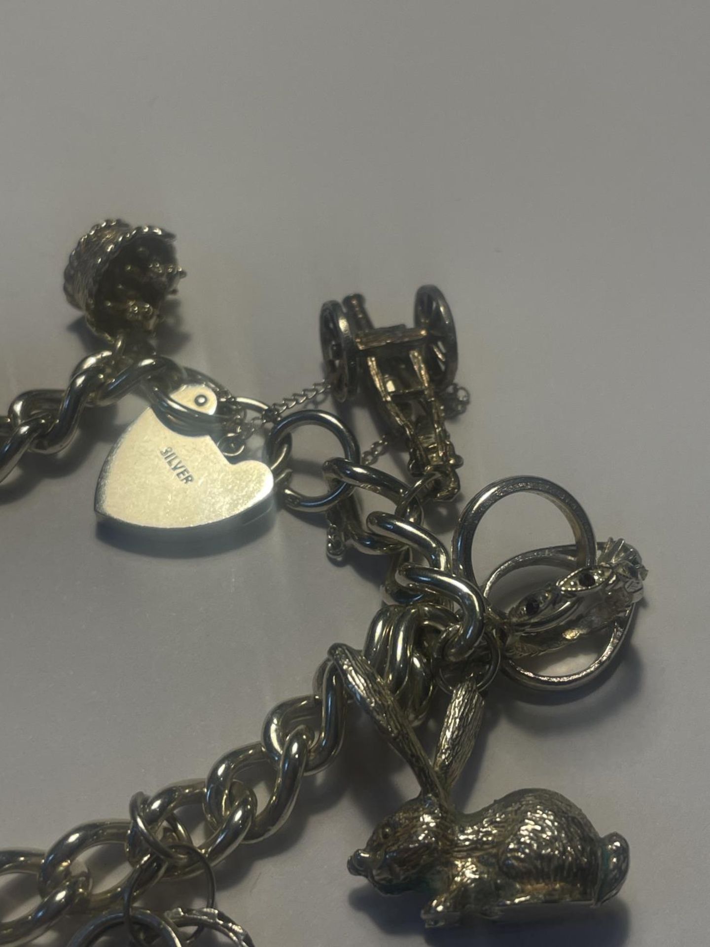 A SILVER CHARM BRACELET WITH ELEVEN CHARMS AND A HEART LOCK - Image 3 of 4