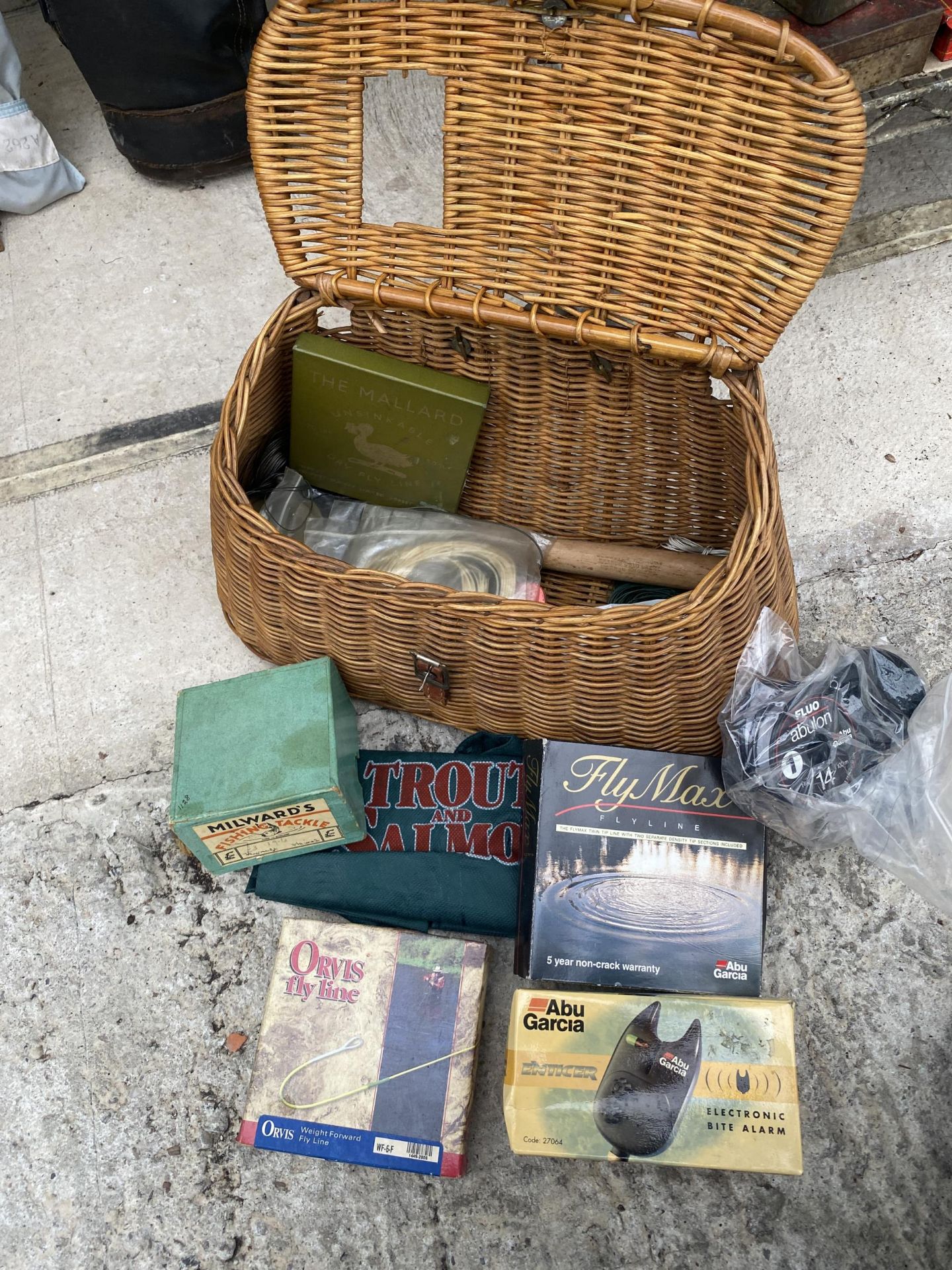 A WICKER TACLE BOX CONTAINING FISHING ITEMS TO INCLUDE A REEL AND A BITE ALARM ETC