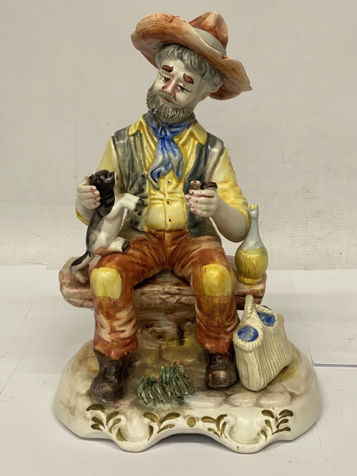 A CAPODIMONTE FIGURE OF A MAN ON A BENCH WITH A CAT