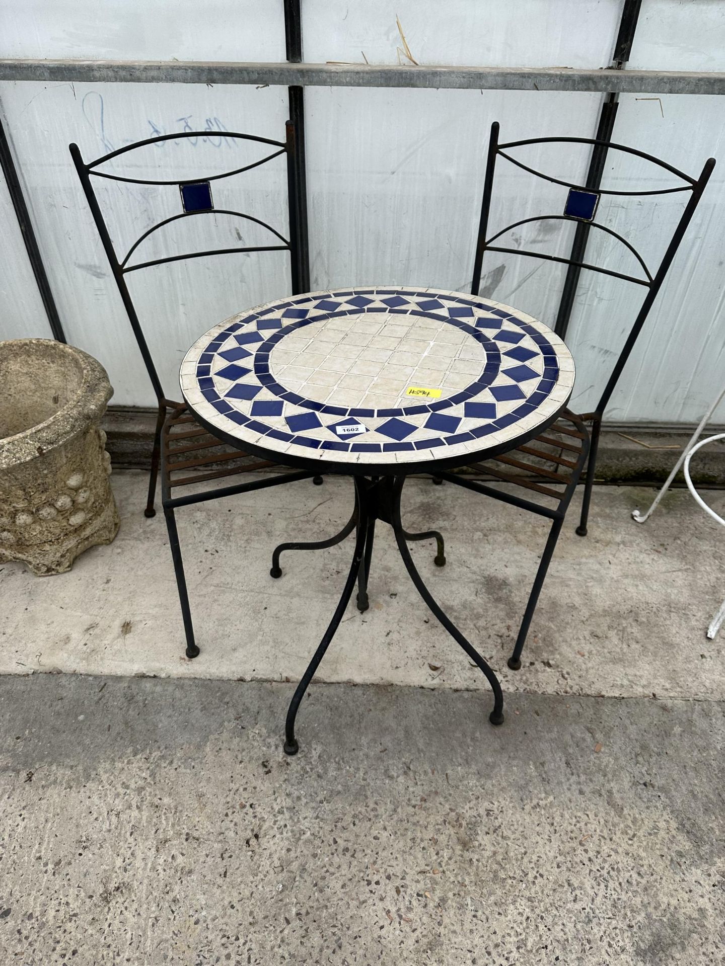 A TILE TOPPED ROUND BISTRO TABLE WITH TWO FOLDING CHAIRS