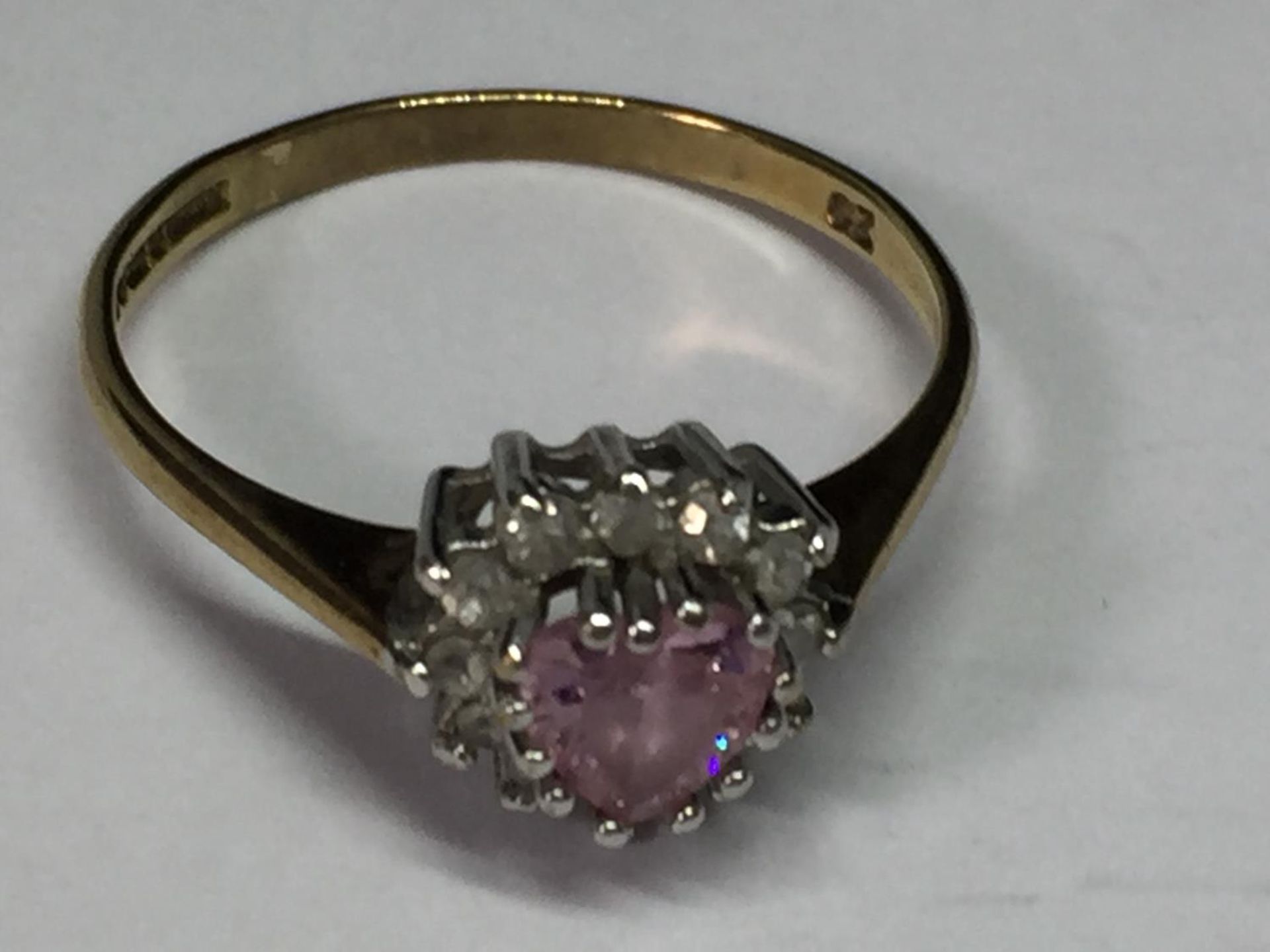 A 9 CARAT GOLD RING WITH A PINK HEART CENTRE STONE SURROUNDED BY CUBIC ZIRCONIAS SIZE O