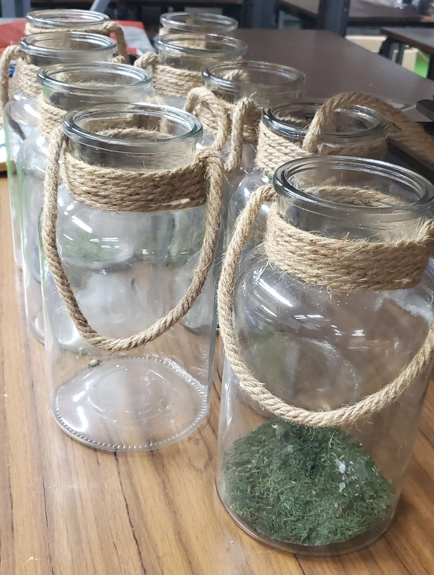 A GROUP OF NINE GLASS JARS WITH ROPE HANGING DESIGN