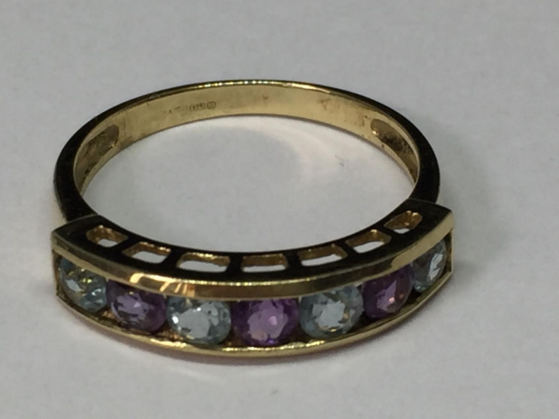 A 9 CARAT GOLD RING WITH FOUR AQUAMARINES AND THREE AMETHYSTS IN A LINE SIZE M/N