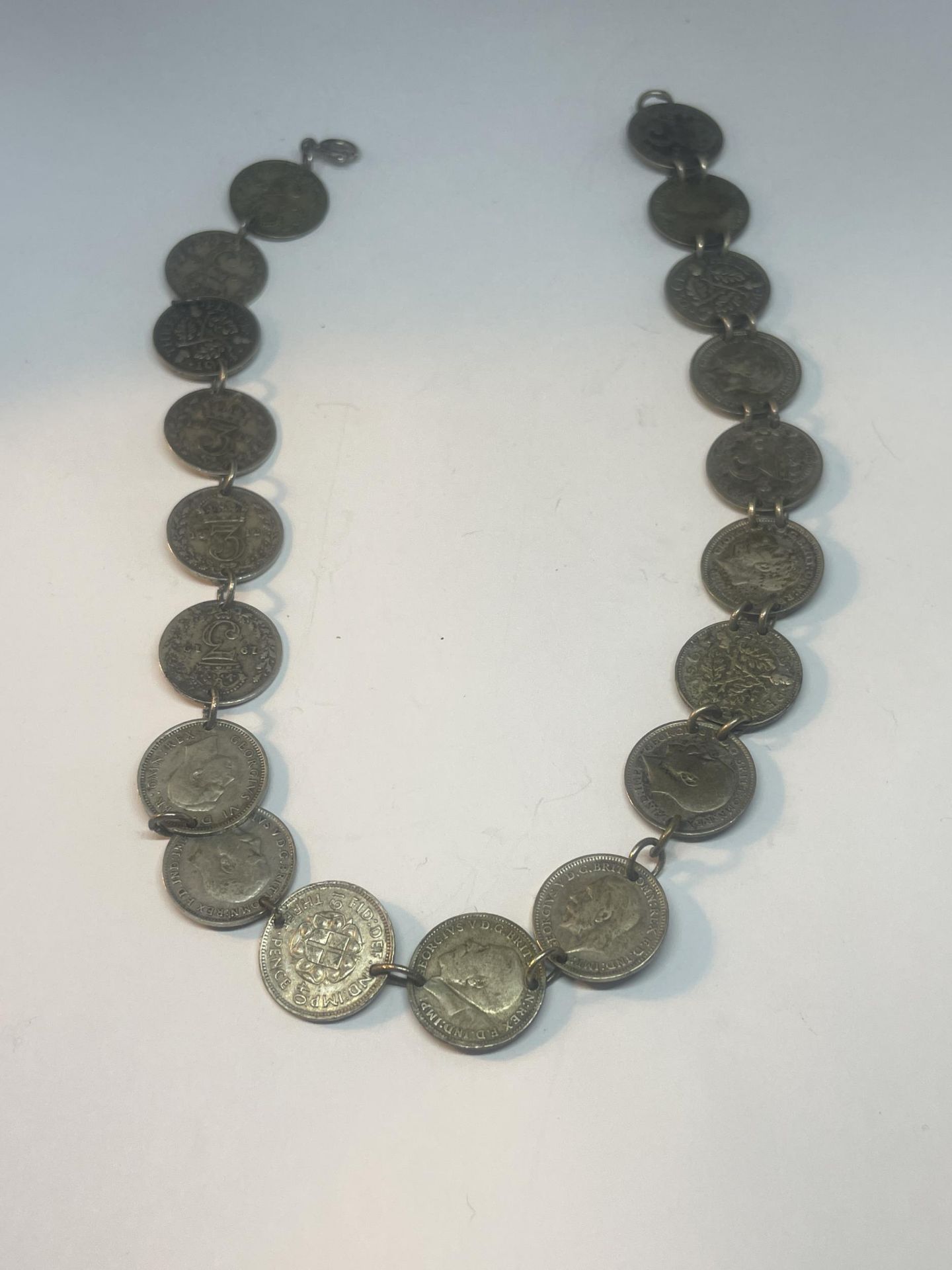 A NECKLACE MADE UP OF NINETEEN SILVER THREE PENCES