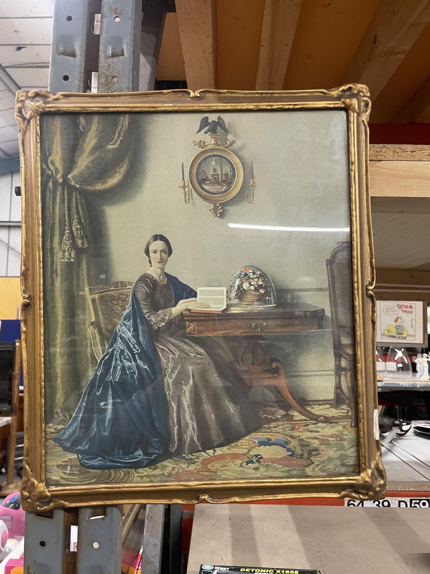 A GILT FRAMED PRINT OF A LADY IN HER DRAWING ROOM