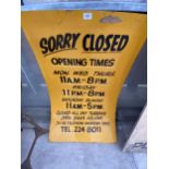 A WOODEN ' SORRY CLOSED, OPENING TIMES' SIGN