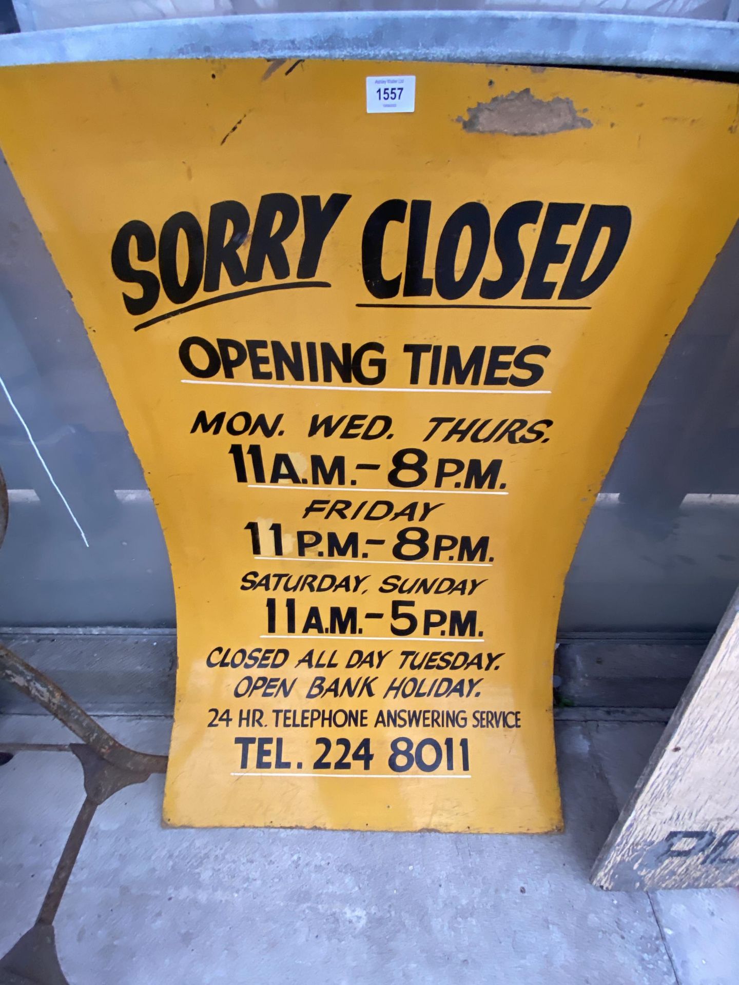 A WOODEN ' SORRY CLOSED, OPENING TIMES' SIGN