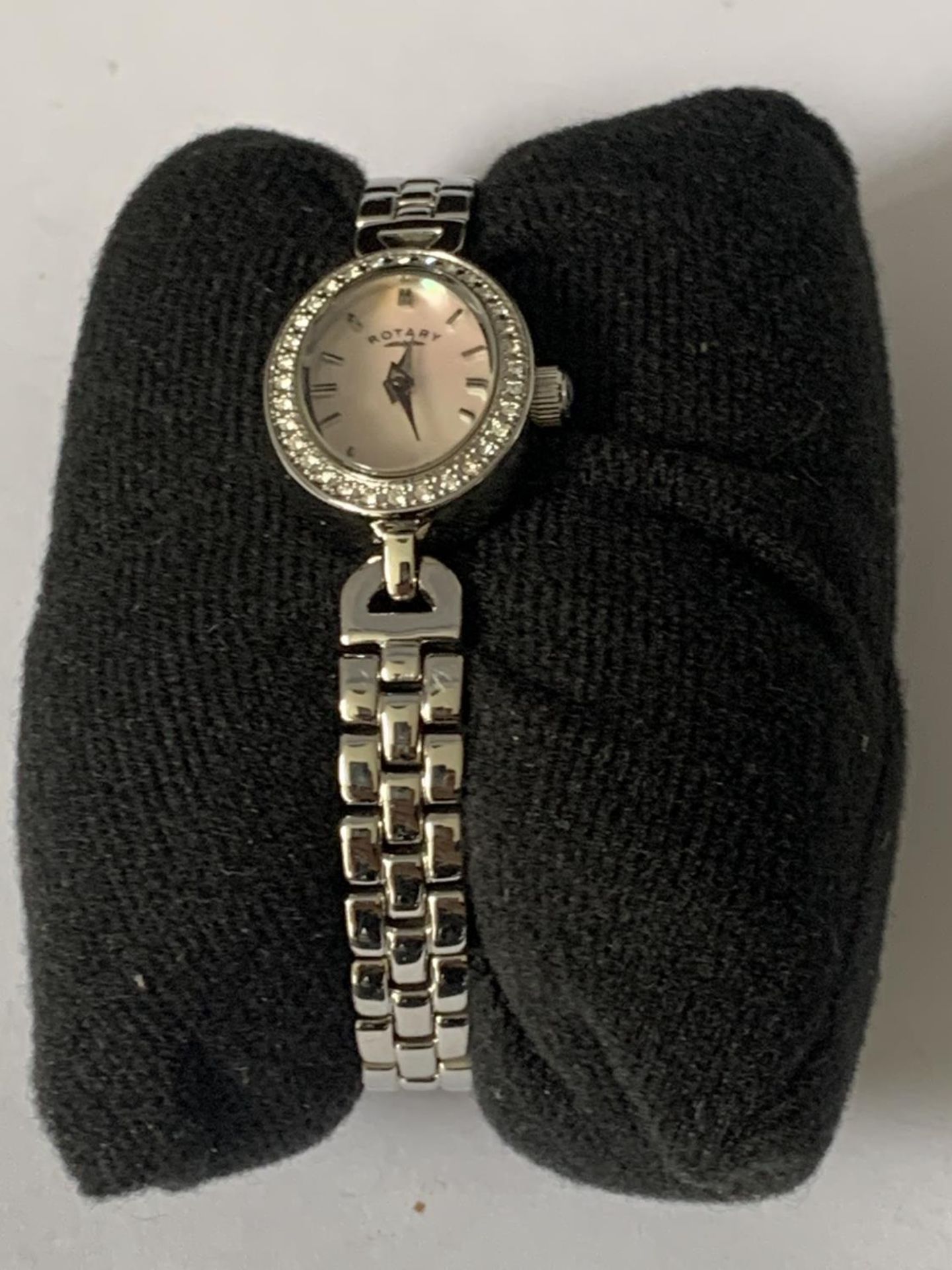 A ROTARY WRIST WATCH WITH PINK MOTHER OF PEARL OVAL FACE SURROUNDED BY CLEAR STONES