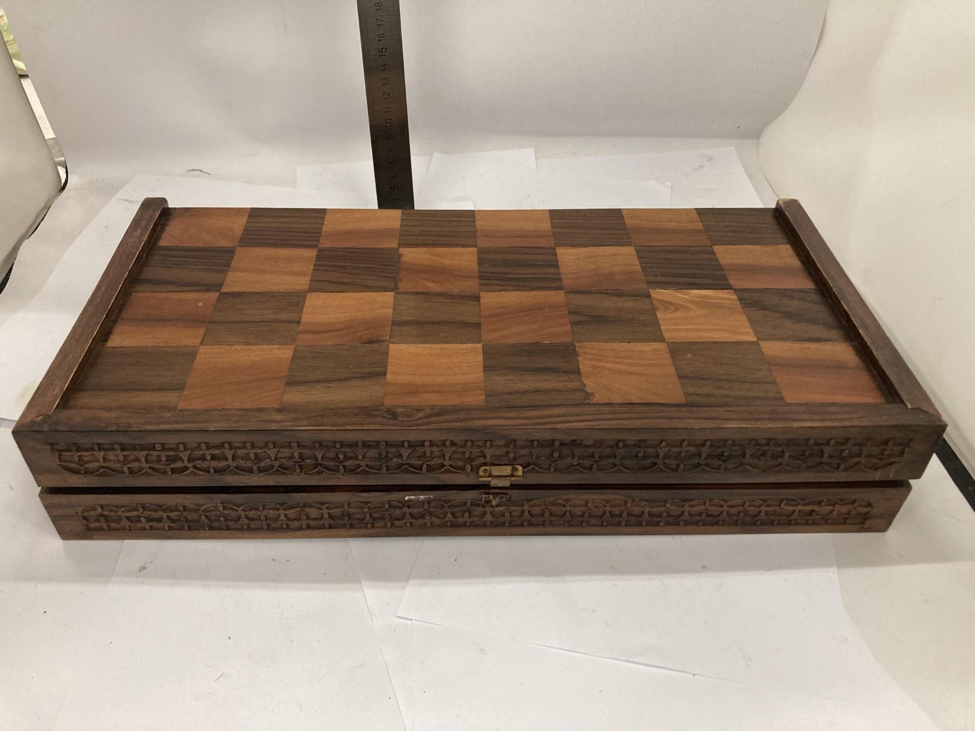 A VINTAGE HARDWOOD CHESS BOARD WITH CARVED WOODEN PIECES