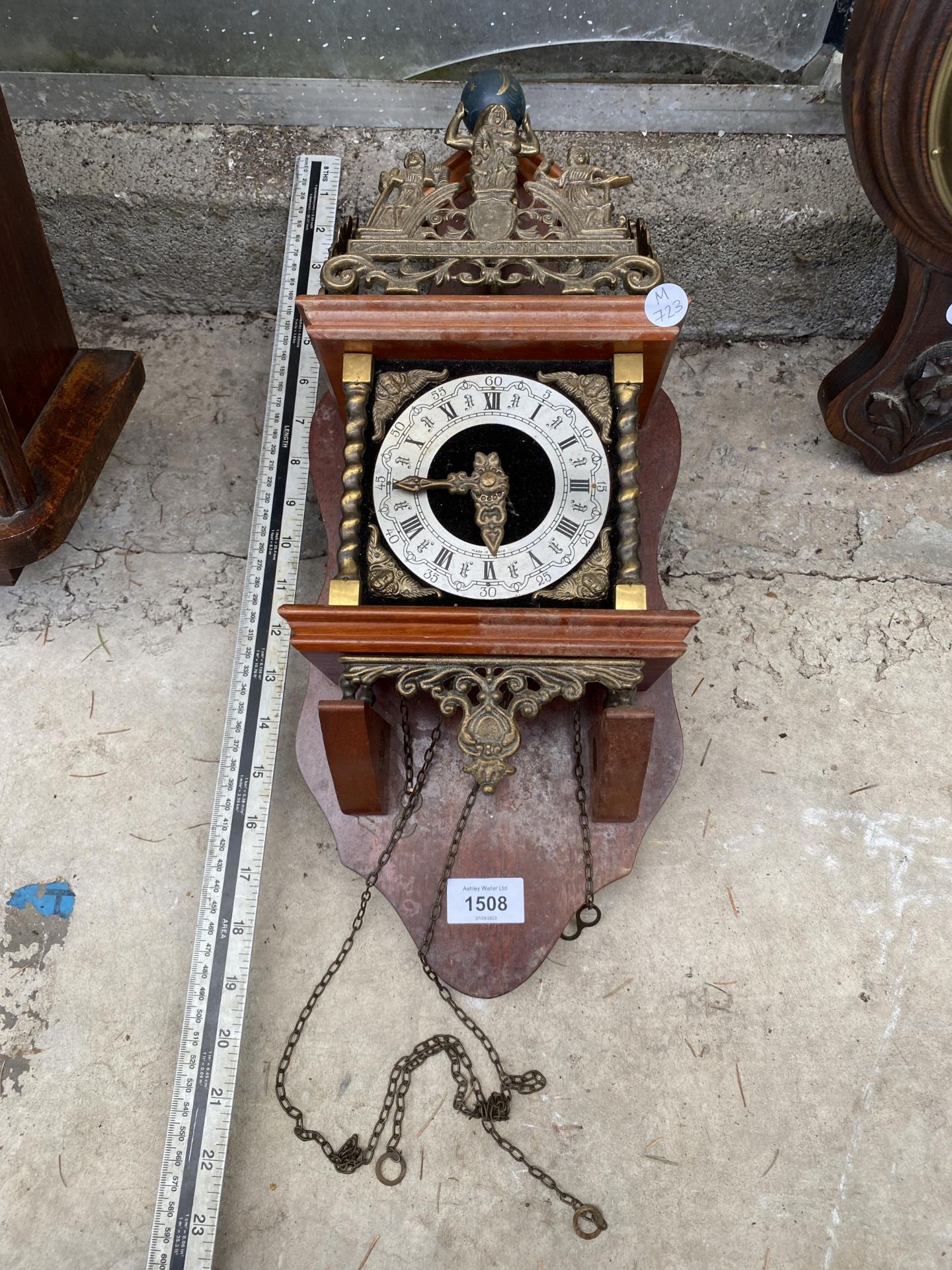 A DECORATIVE WOODEN WALL CLOCK WITH BRASS DETAIL