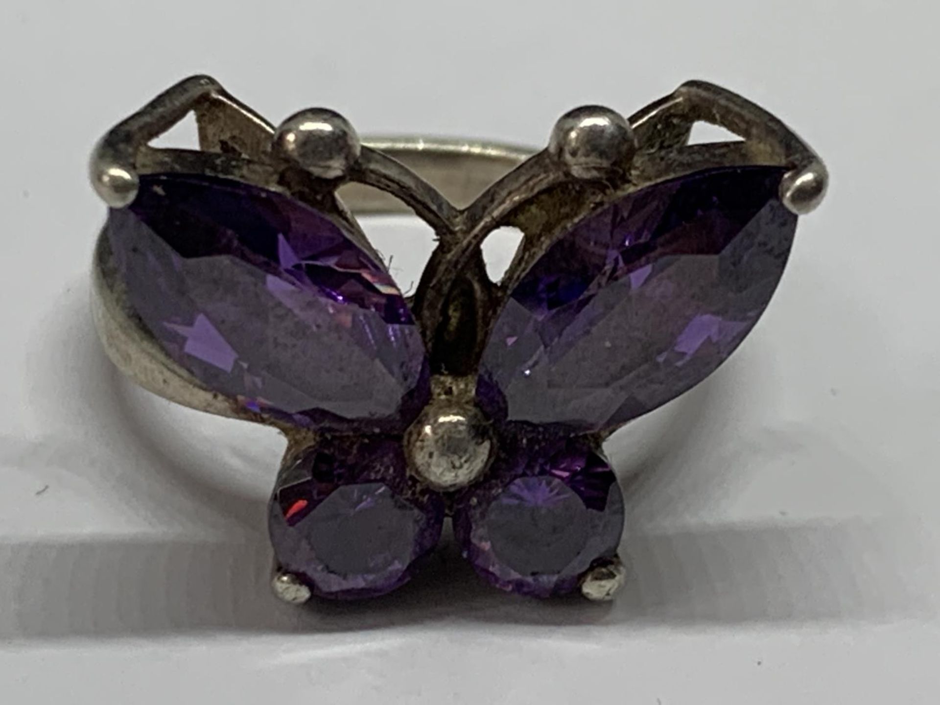 A SILVER RING WITH PURPLE STONES IN A BUTTERFLY DESIGN SIZE M IN A PRESENTATION BOX