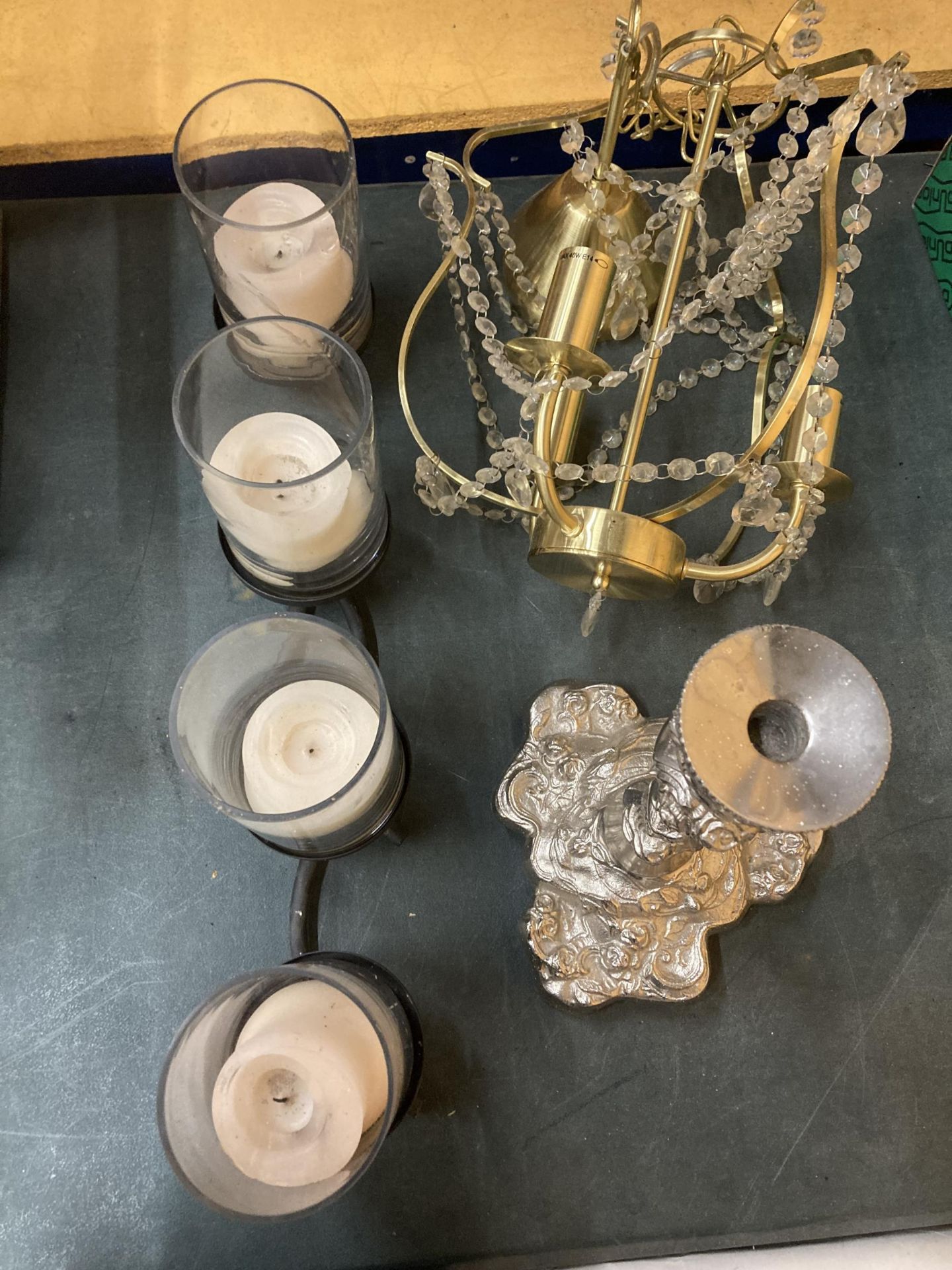 A LARGE METAL CANDLE HOLDER HOLDING FOUR LARGE CANDLES IN GLASS HOLDERS, A LARGE SILVER COLOURED