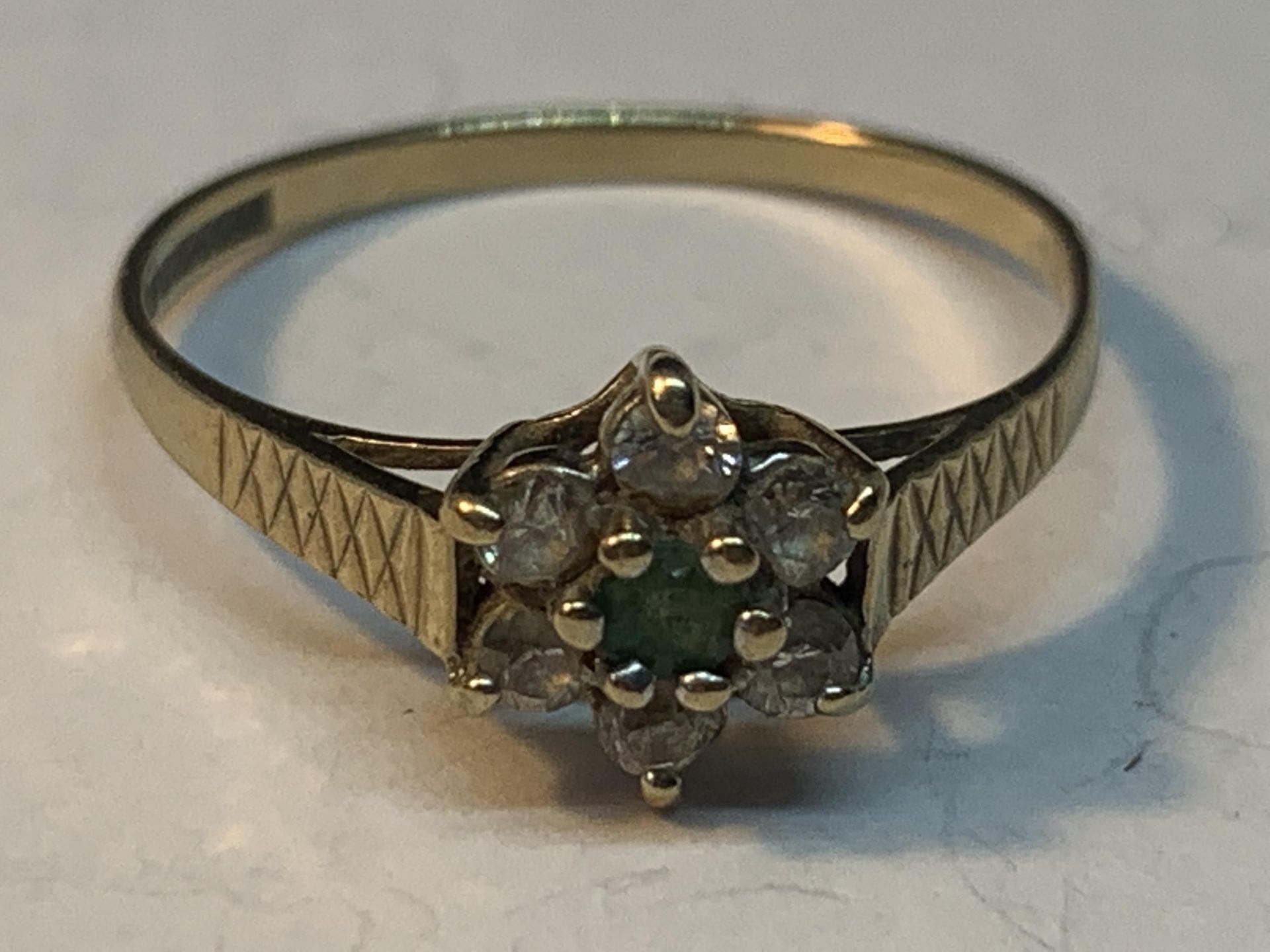 A 9 CARAT GOLD RING WITH CENTRE EMERALD SURROUNDED BY CUBIC ZIRCONIAS SIZE O