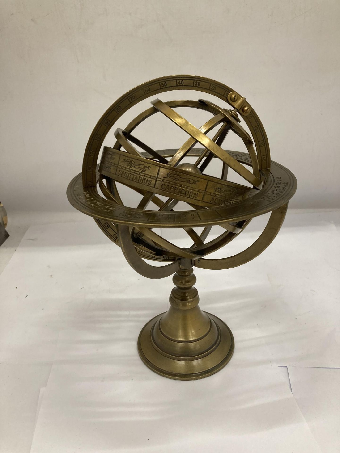 A BRASS DESK REVOLVING GLOBE STYLE COMPASS WITH BIRTH SIGNS