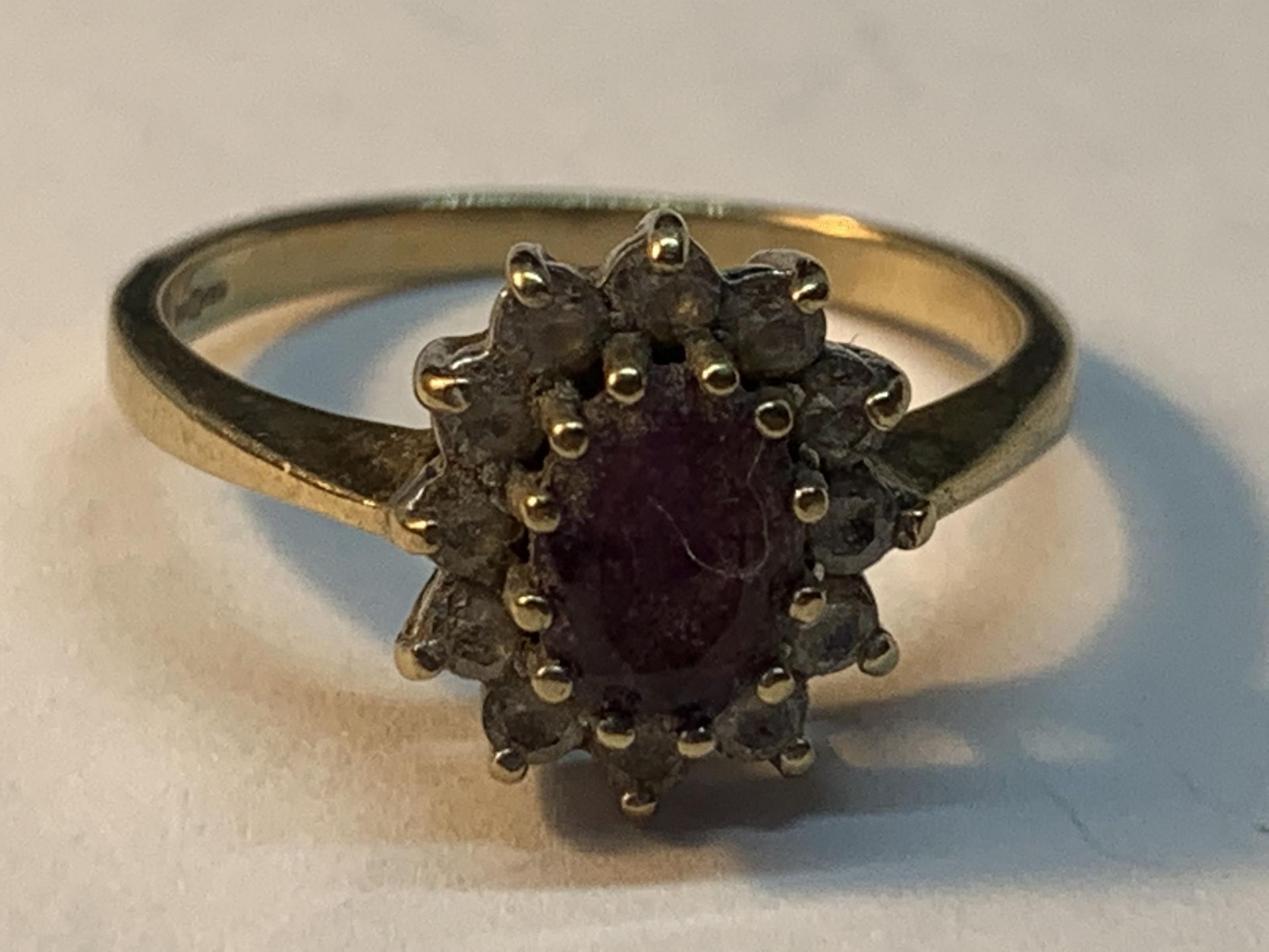 A 9 CARAT GOLD RING WITH CENTRE AMETHYST SURROUNDED BY CUBIC ZIRCONIAS SIZE N/O