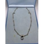 A SILVER NECKLACE WITH A BLACK STONE IN A PRESENTATION BOX