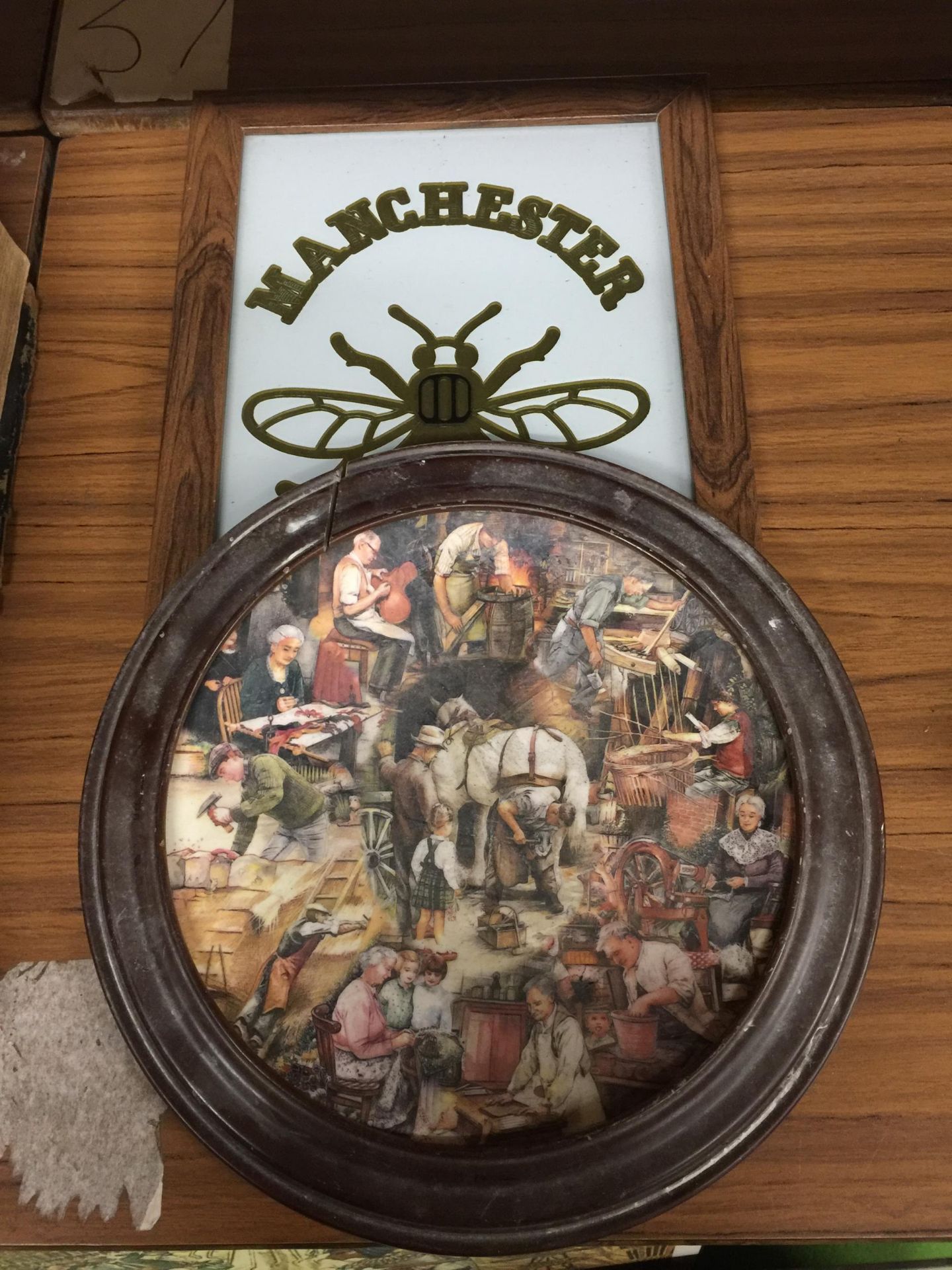 A MANCHESTER 'BEE' PICTURE PLUS A FRAMED CERAMIC BLACKSMITH PLATE