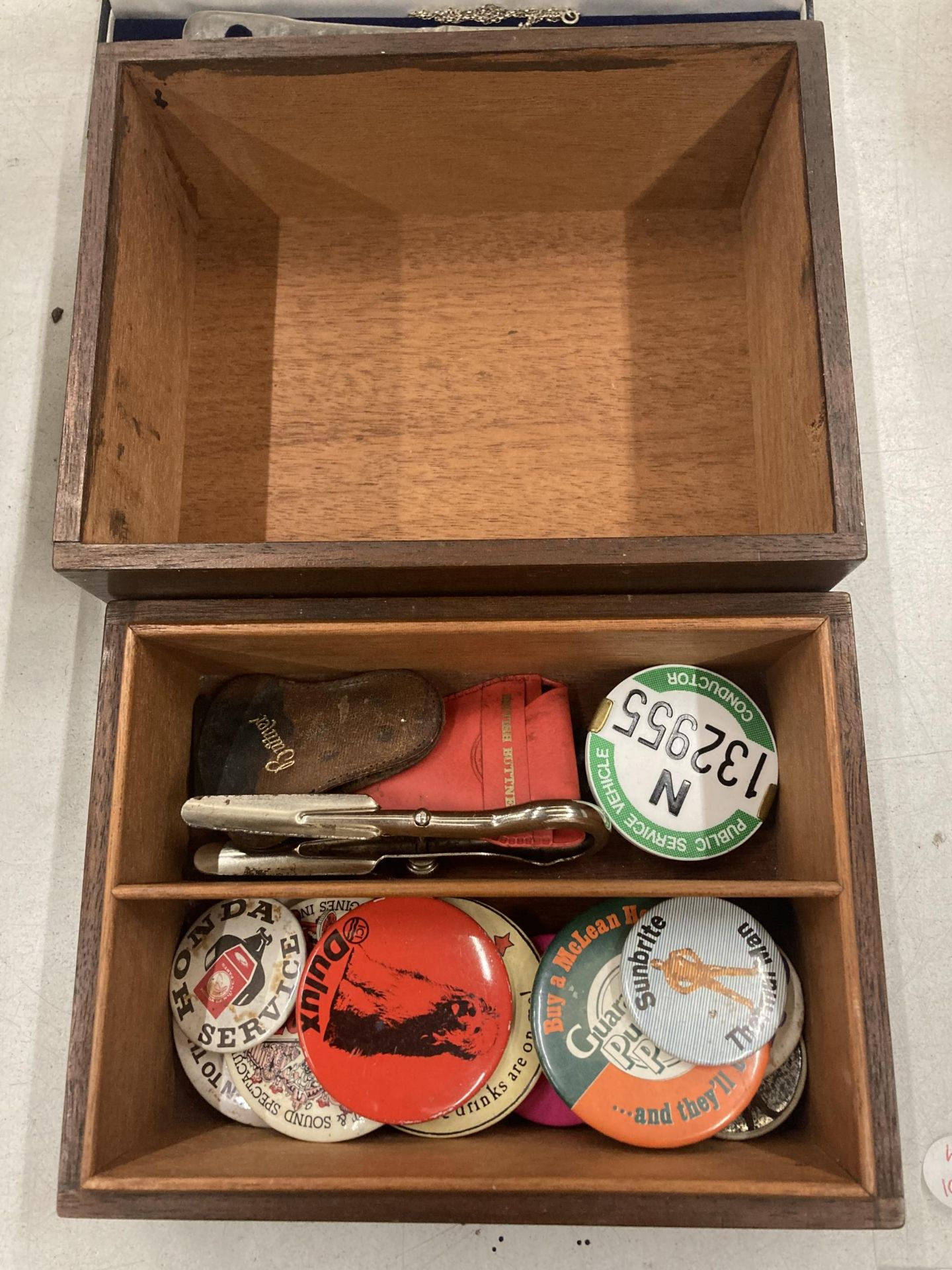 A WOODEN BOX CONTAINING ASSORTED BADGES, CAR BADGES ETC