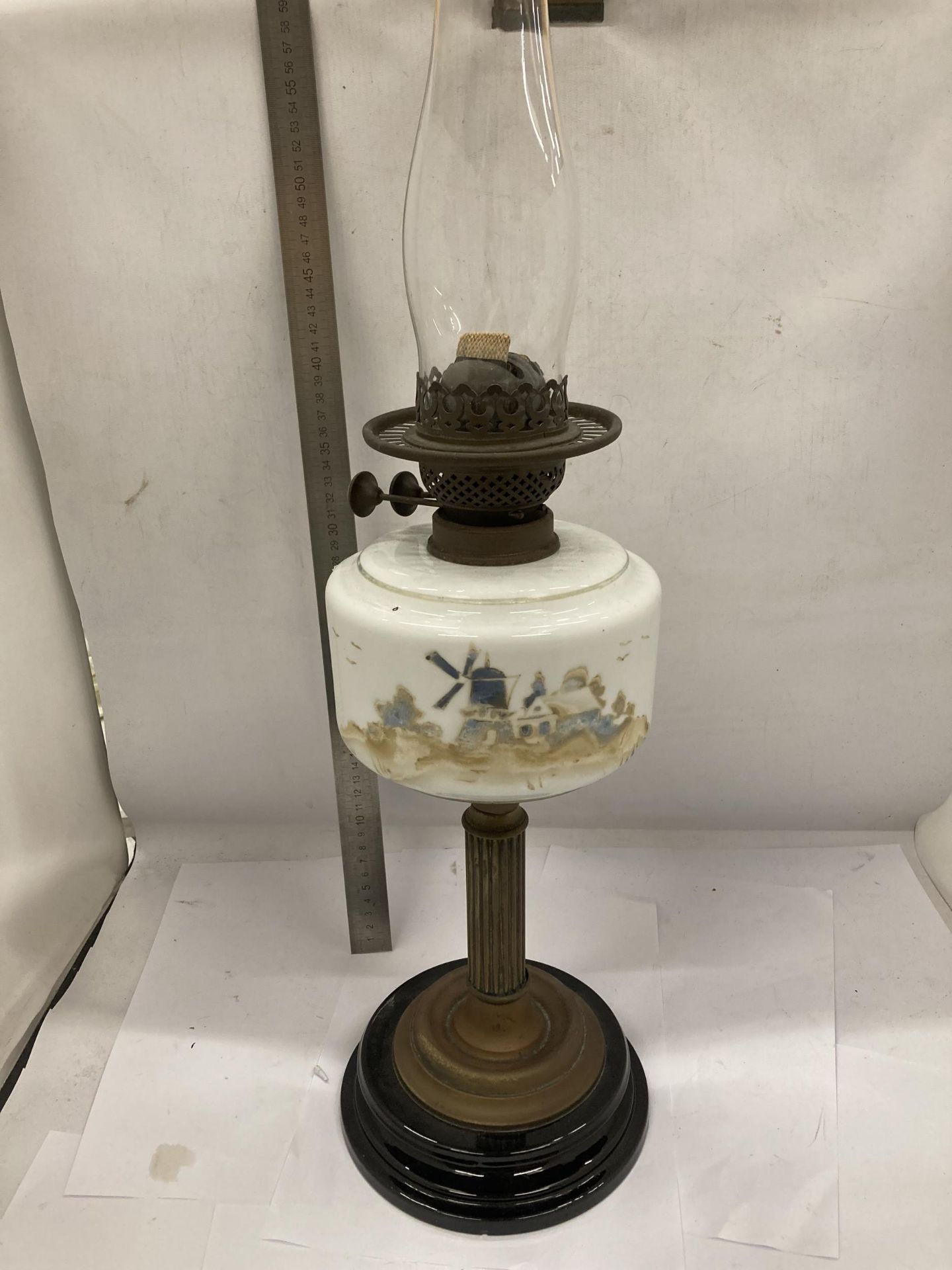A VINTAGE OIL LAMP WITH BRASS CORINTHIAN COLUMN SUPPORT AND PAINTED WINDMILL SCENE RESEVOIR