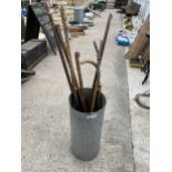 A GALVANISED STICK STAND AND AN ASSORTMENT OF WALKING STICKS