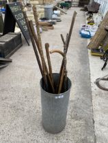 A GALVANISED STICK STAND AND AN ASSORTMENT OF WALKING STICKS