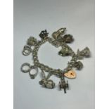 A SILVER CHARM BRACELET WITH ELEVEN CHARMS AND A HEART PADLOCK