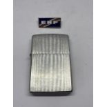 A MADE IN USA ZIPPO LIGHTER AND AN ENAMEL ERF BADGE