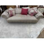 A TWEED UPHOLSTERED BUTTON BACK CHESTERFIELD TYPE THREE SEATER SOFA ON BRASS CASTOR SUPPORTS