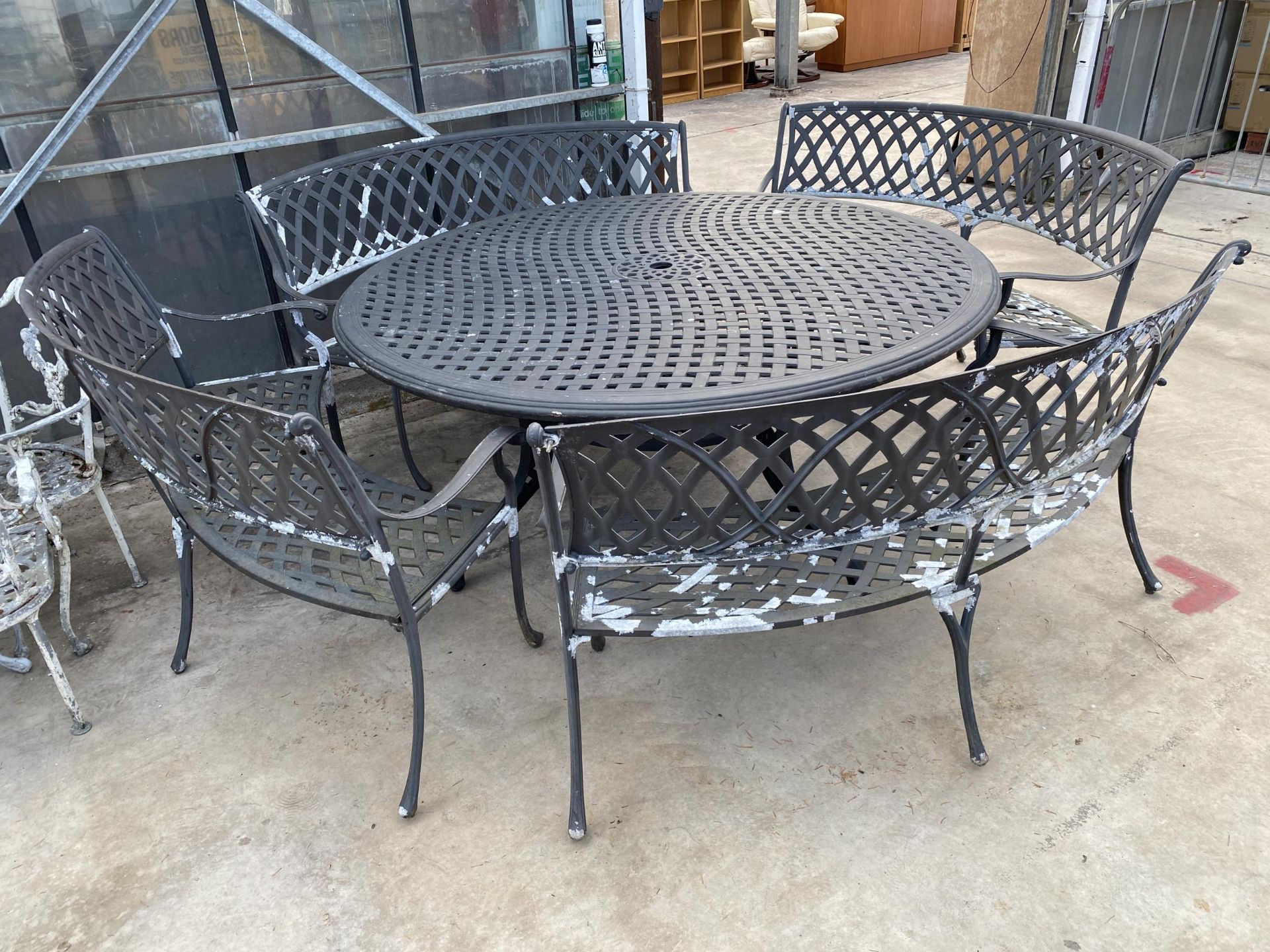 A LARGE CAST ALLOY PATIO FURNITURE SET COMPRISING OF A ROUND TABLE AND FOUR CURVED TWO SEATER