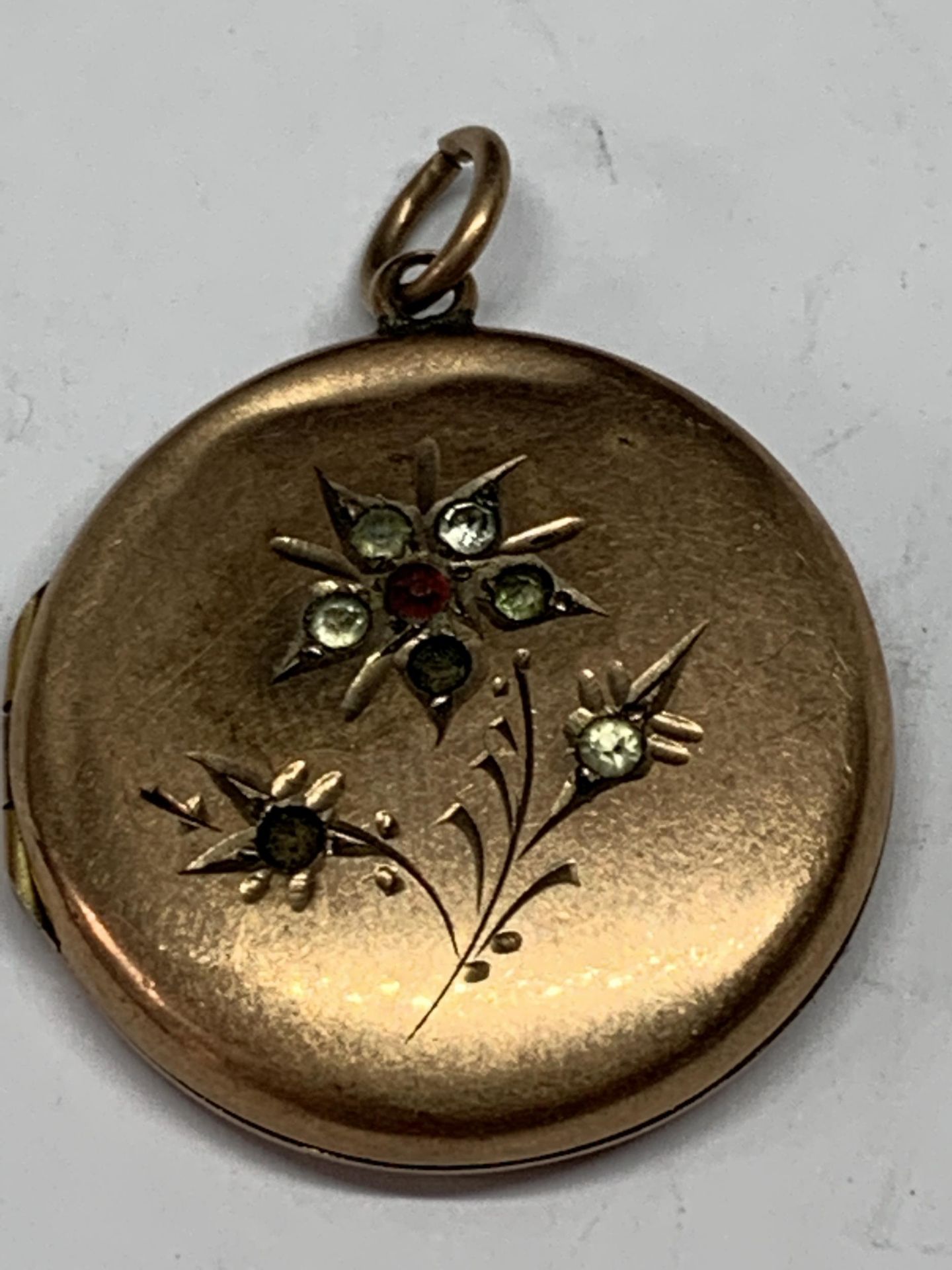 A 9 CARAT GOLD LOCKET WITH COLOURED STONE FLOWER DECORATION