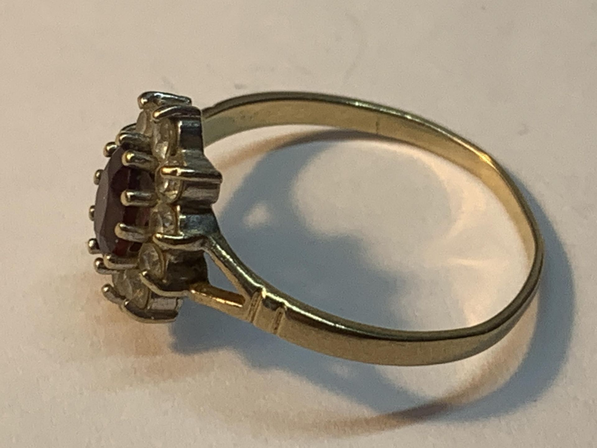 A 9 CARAT GOLD RING WITH A CENTRE GARNET SURROUNDED BY CUBIC ZIRCONIAS SIZE O/P - Image 2 of 3