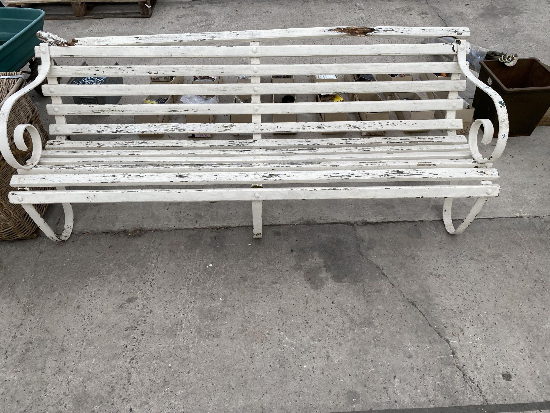 A THREE SEATER WOODEN SLATTED GARDEN BENCH WITH SCROLL METAL ENDS AND MIDDLE SUPPORT