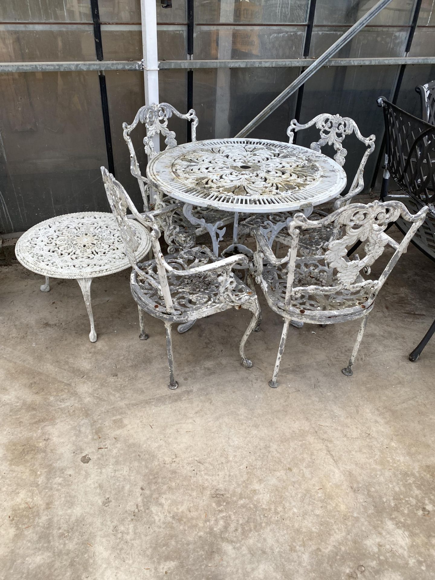 A VINTAGE CAST ALLOY BISTRO SET COMPRISING OF A ROUND TABLE, FOUR CARVER CHAIRS AND A COFFEE TABLE