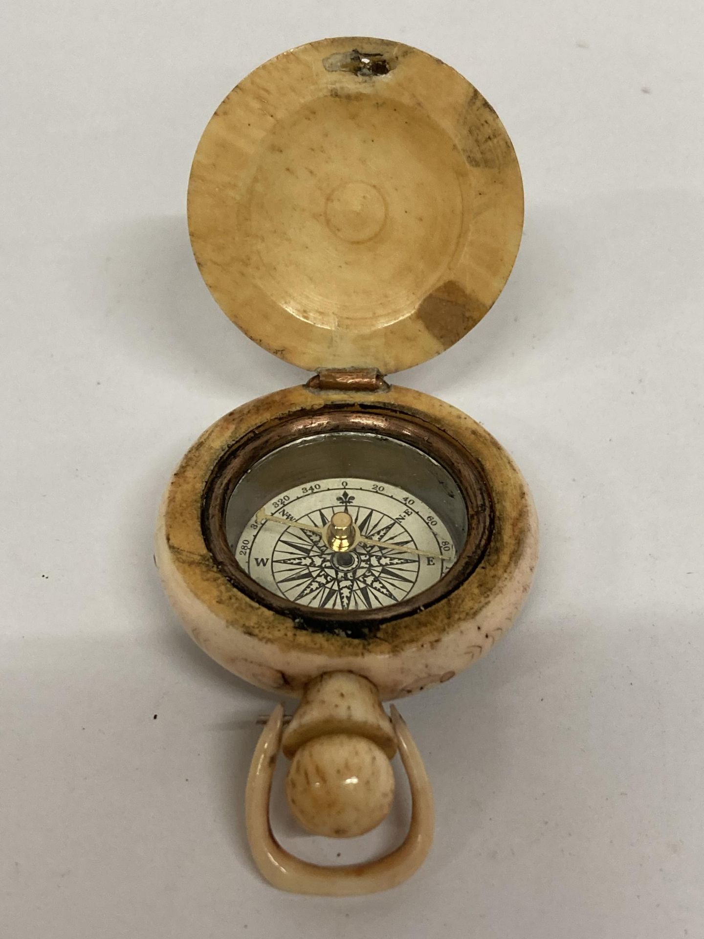 A BONE CARVED SWEET HEARTS COMPASS WITH BIRD AND FIGURES DESIGN