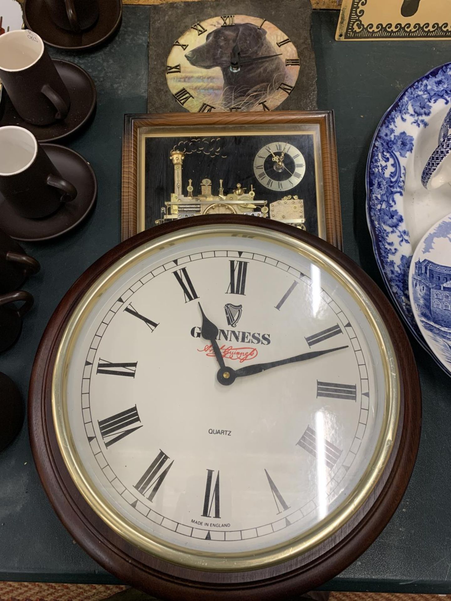 A LARGE 'GUINNESS' QUARTZ WALL CLOCK, DIAMETER 38CM, A SLATE WALL CLOCK WITH THE IMAGE OF A BLACK