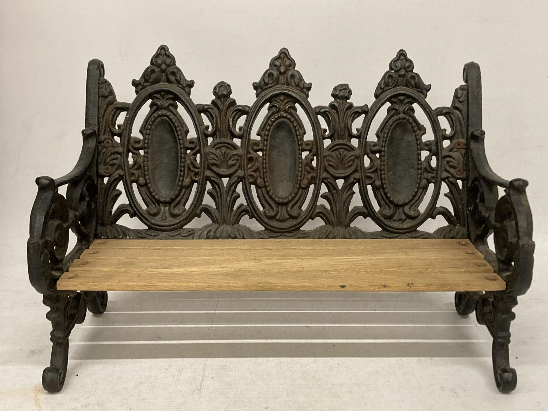 A TABLE TOP CAST VICTORIAN STYLE BENCH WITH WOODEN SLATTED SEAT