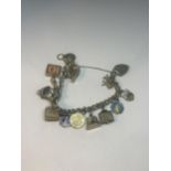 A SILVER CHARM BRACELET WITH FIFTEEN CHARMS AND A HEART PADLOCK