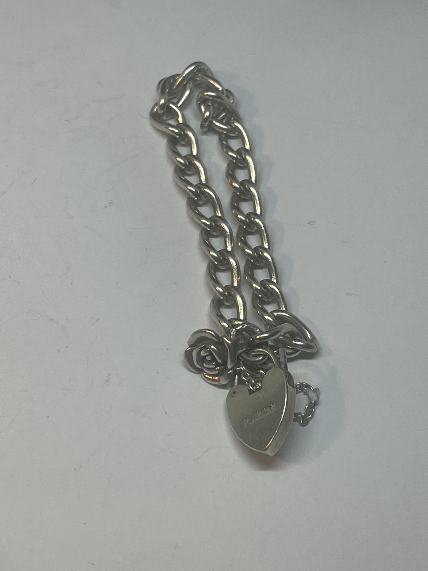 A SILVER WRIST CHAIN WITH ROSE CHARM WITH SILVER HEART PADLOCK