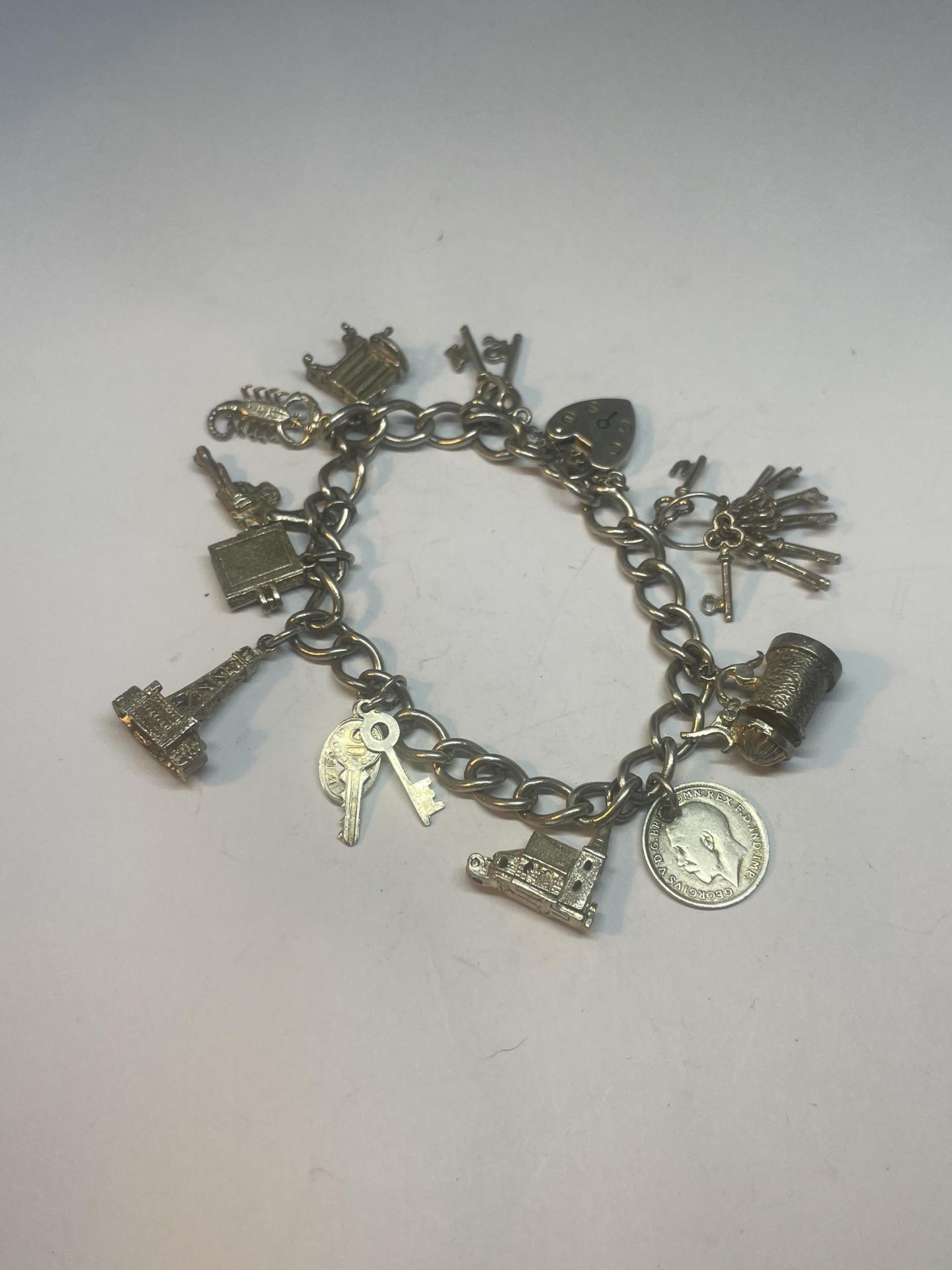 A SILVER CHARM BRACELET WITH ELEVEN CHARMS AND A HEART PADLOCK