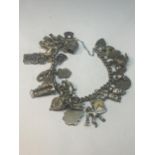 A SILVER CHARM BRACELET WITH TWENTY FIVE CHARMS AND A HEART PADLOCK