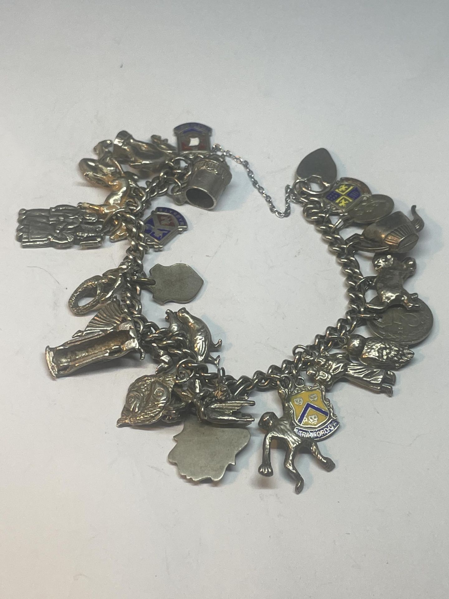 A SILVER CHARM BRACELET WITH TWENTY FIVE CHARMS AND A HEART PADLOCK