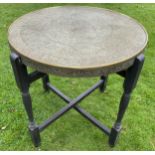 A MIDDLE EASTERN BRASS CIRCULAR TOPPED TABLE ON FOLDING WOODEN BASE, DIAMETER 59CM