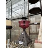 A CAST IRON AND CRANBERRY GLASS OIL LAMP