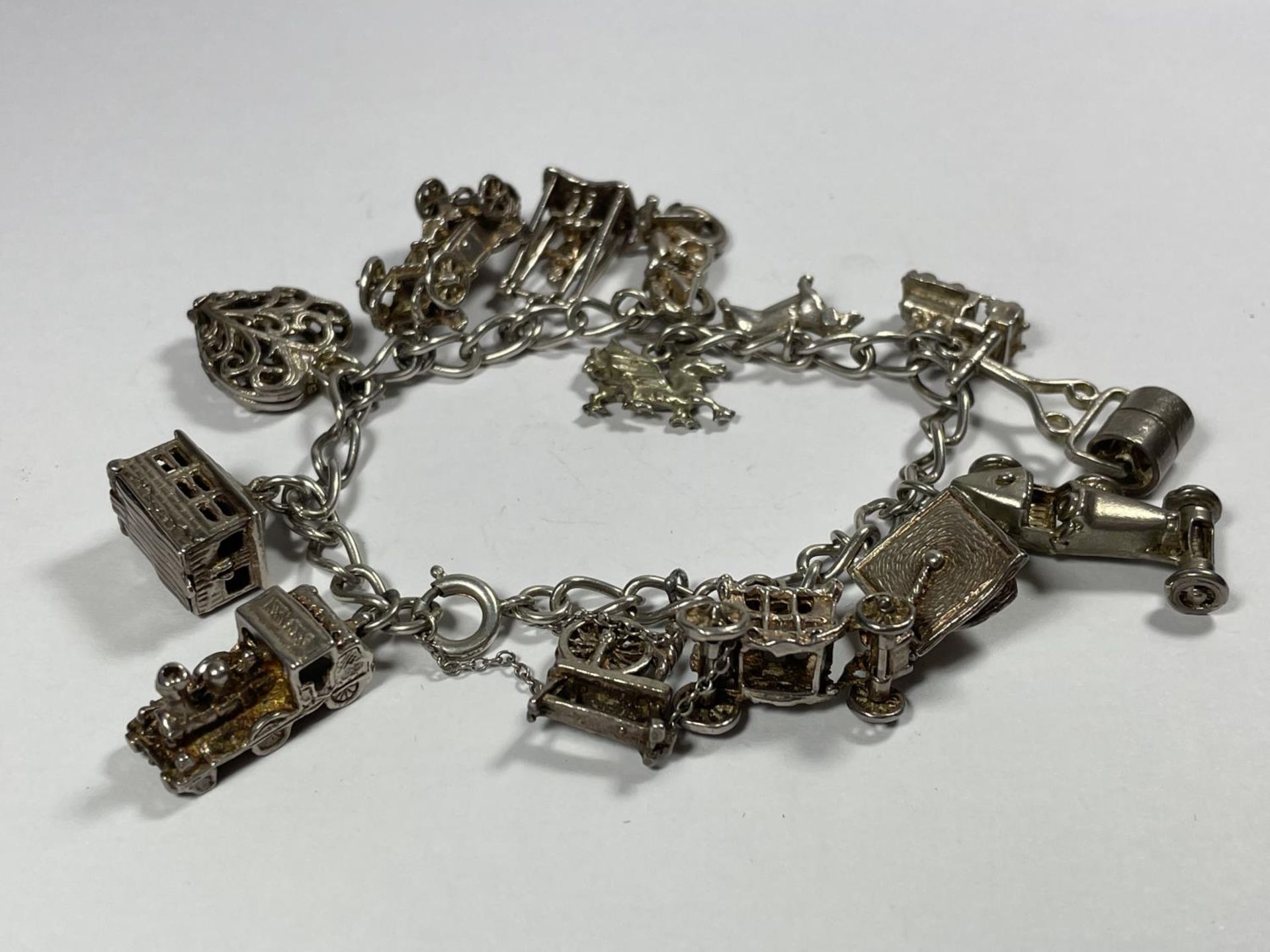 A HEAVY SILVER CHARM BRACELET WITH FOURTEEN CHARMS