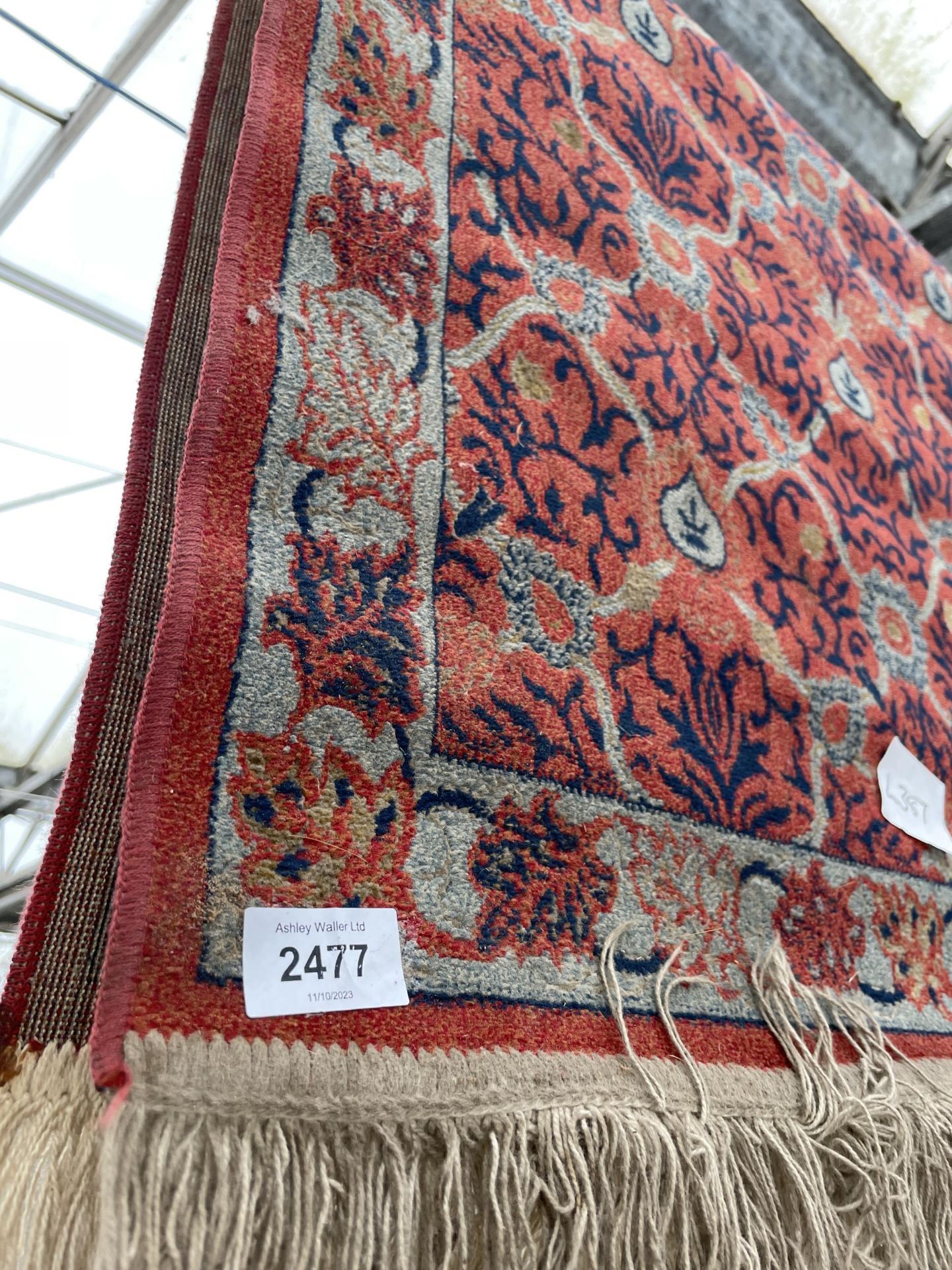 A SMALL RED PATTERNED FRINGED RUG - Image 2 of 2