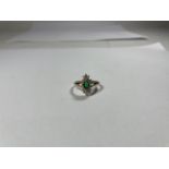 A 9 CARAT GOLD RING WITH CENTRE GREEN STONE SURROUNDED BY CUBIC ZIRCONIAS IN A DIAMOND SHAPE SIZE