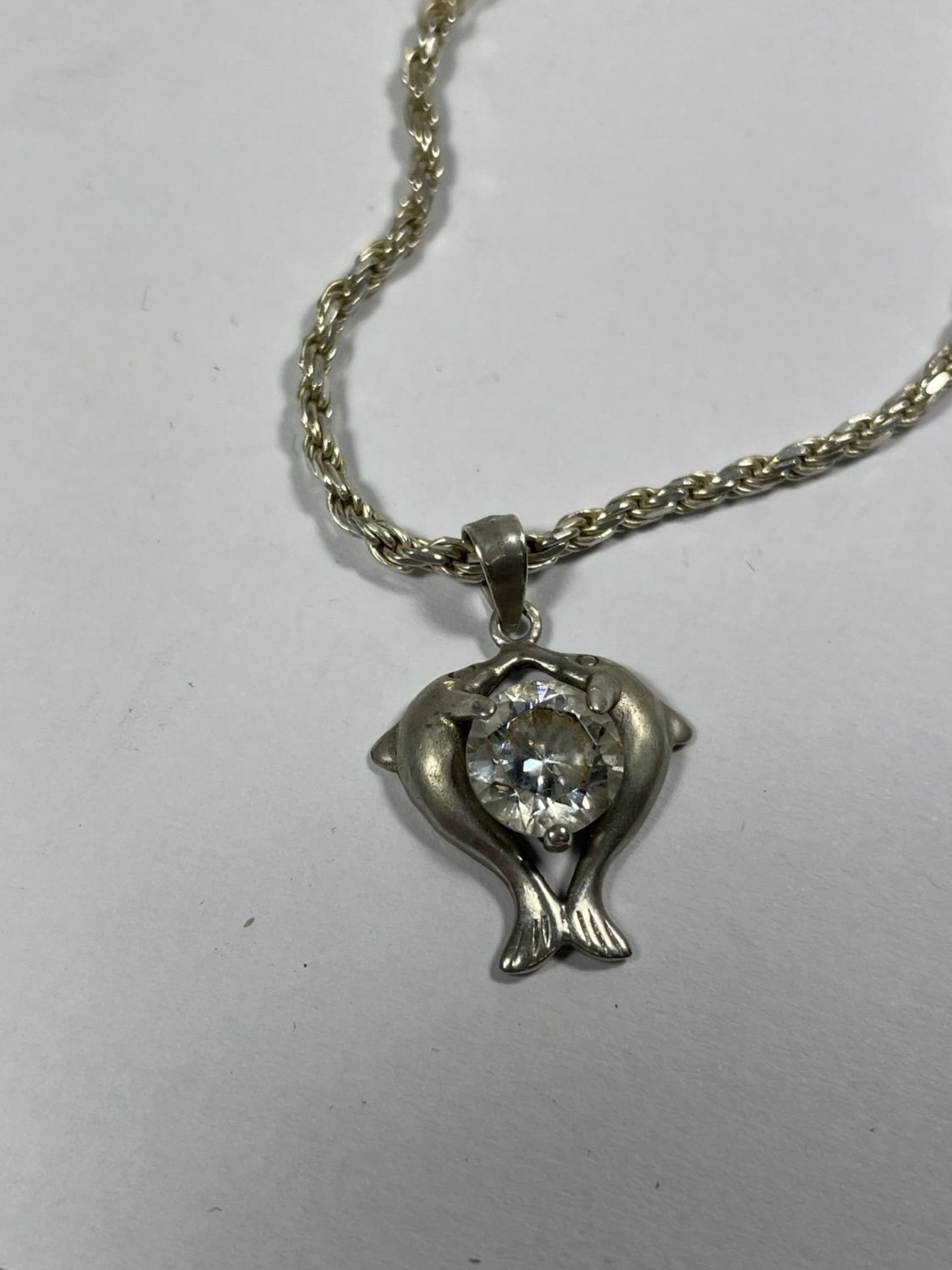 A SILVER NECKLACE WITH A DOUBLE DOLPHIN AND CLEAR STONE PENDANT AND A DOUBLE DOLPHIN RING IN A - Image 3 of 5