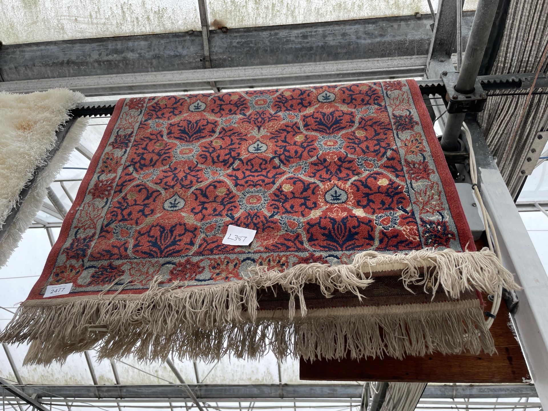 A SMALL RED PATTERNED FRINGED RUG