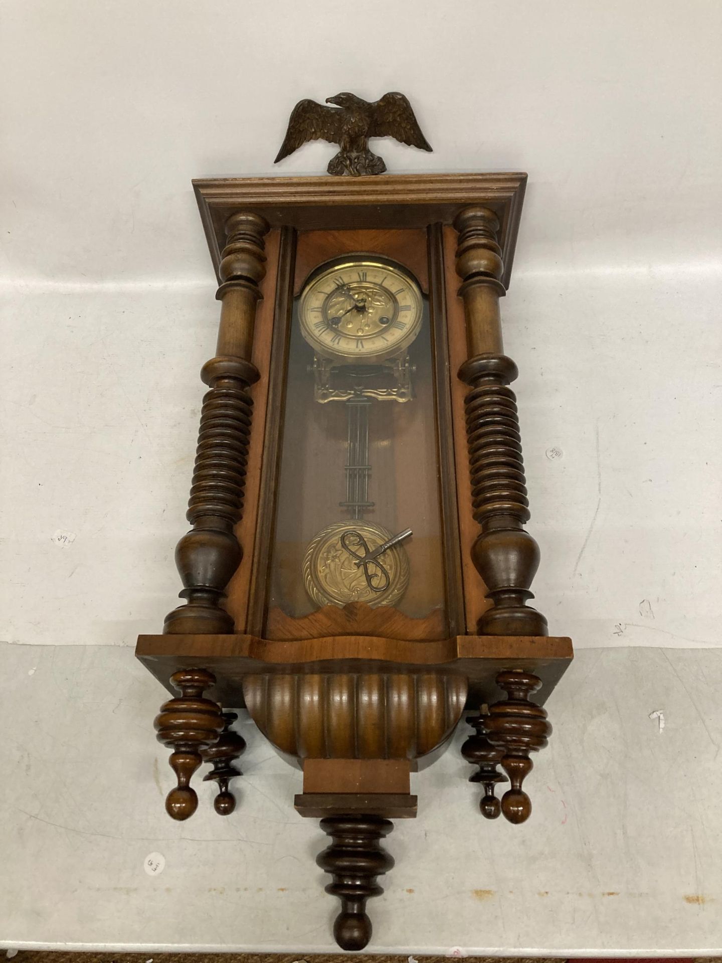 A MAHOGANY CASED VIENNA WALL CLOCK WITH EAGLE DESIGN TOP, WITH PENDULUM AND KEY